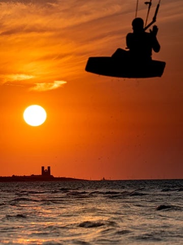 Minnis Bay and sun setting over Reculver Towers with jumping kitesurfer  9